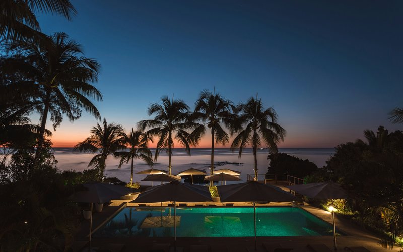 Hotel pool and palm trees at dusk